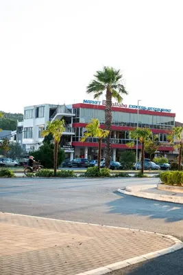 a large building with palm trees in front of a street at Amarea Apartments in Ulcinj