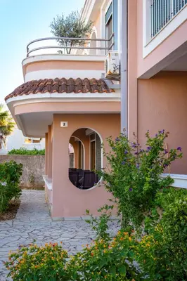 a pink building with a round window and a balcony at Apartments Noki in Ulcinj