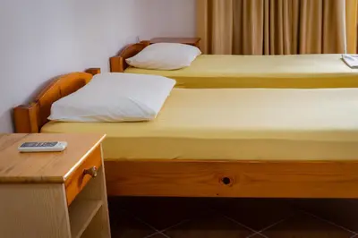 two twin beds in a room with a desk at Apartments Noki in Ulcinj