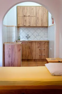 a kitchen with wooden cabinets and a yellow bed in a room at Apartments Noki in Ulcinj