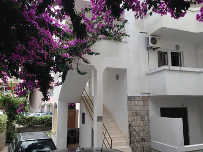 a white building with stairs and purple flowers at Guest House Violet in Becici