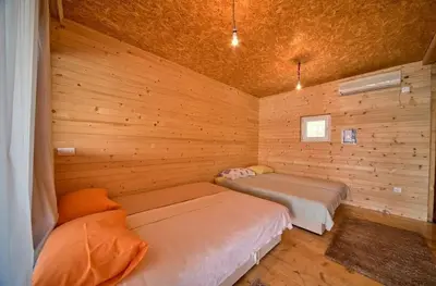 two beds in a room with wooden walls at Sunset 4 in Ada