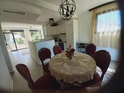 a dining room table with red chairs and a kitchen at Villa Nuna in Bar