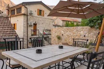 a table with chairs and an umbrella on a patio at Apartments Račić in Kotor