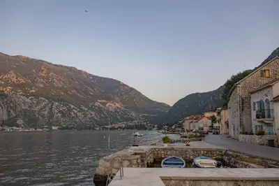 a town next to a body of water with mountains at Apartments Račić in Kotor