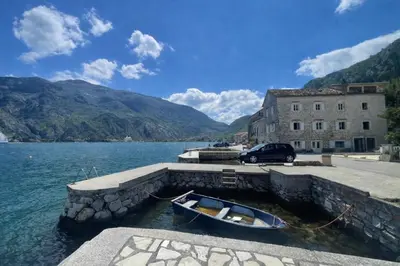 a small boat in the water next to a building at Apartments Račić in Kotor