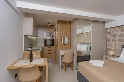 a hotel room with a bed and a desk and a kitchen at Apartments Račić in Kotor