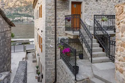 a stone house with stairs and a door and flowers at Apartments Račić in Kotor