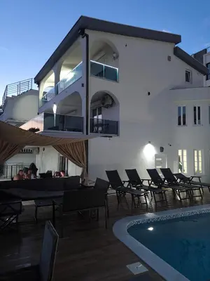 a hotel with a swimming pool and chairs and a building at Vila Eden in Bar