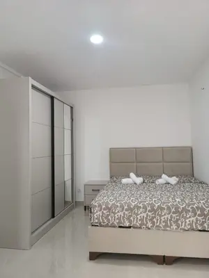 a white bedroom with a bed and a dresser at Vila Eden in Bar