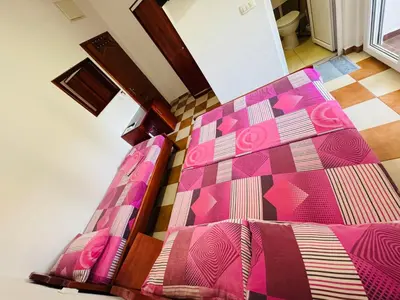 a bed with a pink comforter on top of it at Apartments TRI SRCA in Sutomore