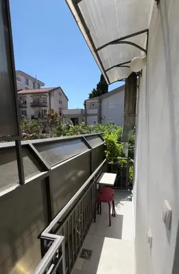 an outdoor balcony with awning and a table and chair at Apartments TRI SRCA in Sutomore