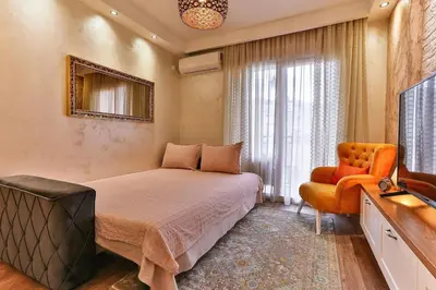 a bedroom with a bed and a chair and a television at Bar- Apartment Prestige in Bjeliši