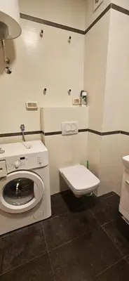 a bathroom with a washing machine and a toilet at Seaside Port Apartments in Bar