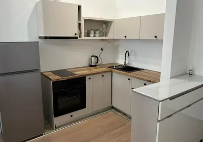 a kitchen with white cabinets and a black stove at Kuc-kuc Twin towers in Becici