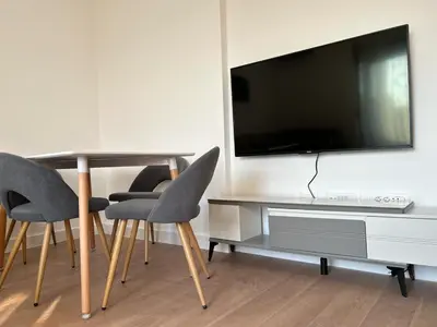 a living room with a table with chairs and a tv at Kuc-kuc Twin towers in Becici