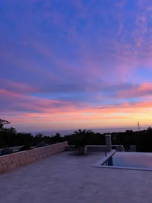 a sunset over a swimming pool on a patio at Villa Maluso in Budva