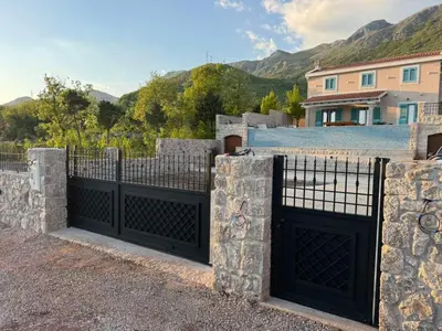 a gate in front of a house with mountains in the background at Villa Maluso in Budva
