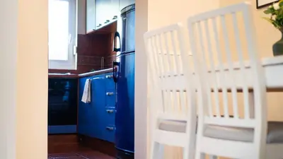 a kitchen with a blue refrigerator and a white chair at Stylish 1 Bedroom Apartment Budva in Budva