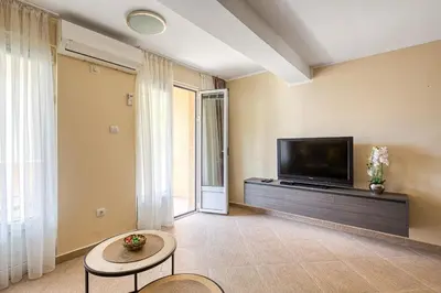 a living room with a flat screen tv and a table at Spacious Comfort in Boreti