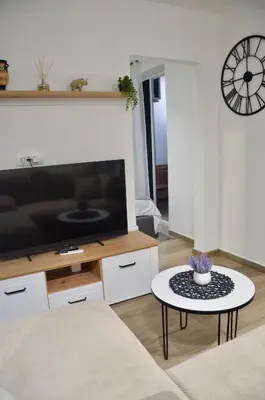a living room with a large tv and a table at Cozy one bedroom apartment with parking in Petrovac na Moru