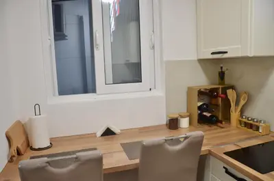 a kitchen with a counter with two chairs and a window at Cozy one bedroom apartment with parking in Petrovac na Moru