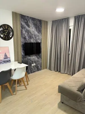 a living room with a table and a clock on a wall at Njaro Del Mar AS in Petrovac na Moru