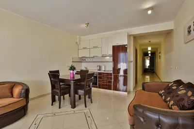 a living room with a table and chairs and a kitchen at Fidel Apartment in Utjeha