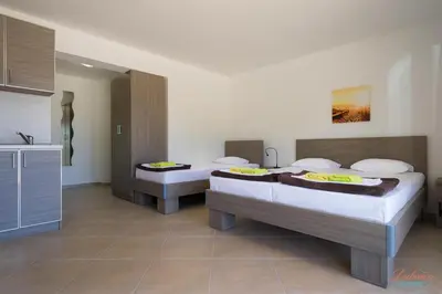 a room with two beds and a sink and a kitchen at Dubrava Sea View Apartments in Dobra Voda