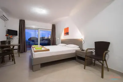 a bedroom with a bed and a desk and a chair at Dubrava Sea View Apartments in Dobra Voda