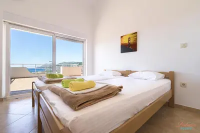 a bedroom with two beds and a large window at Dubrava Sea View Apartments in Dobra Voda