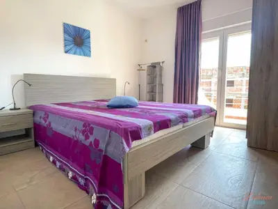 a bedroom with a large bed with a purple blanket at Dubrava Sea View Apartments in Dobra Voda