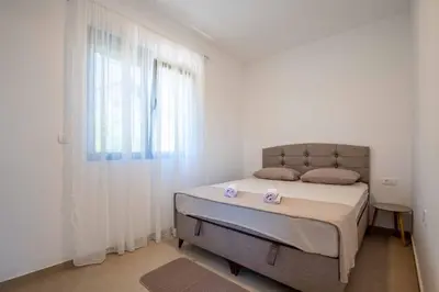 a white bedroom with a bed and a window at Your Adriatic Nest in Bar, Susanj