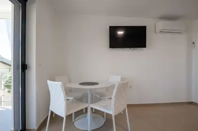 a white table with chairs and a tv on a wall at Your Adriatic Nest in Bar, Susanj