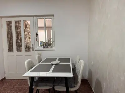 a white dining room with a table and chairs at Apartment Laganini-Bar in Bar, Susanj