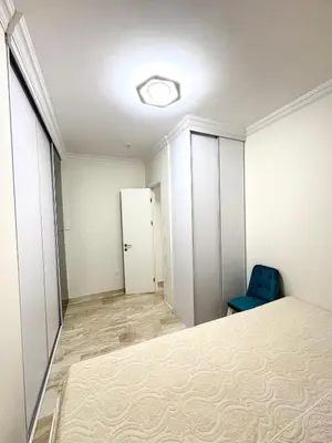 an empty room with a bed and a blue chair at Luxury penthouse in Tre Canne complex in Budva