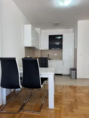 a kitchen with a white table and black chairs at Apartment Gardo in Budva