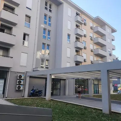a woman standing in front of a large building at Stan Na Dan Podgorica Zabjelo1 in Podgorica