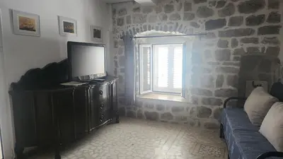 a living room with a tv on a cabinet and a window at Villa Kotor Air in Muo