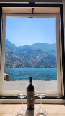 a bottle of wine sitting on a table with two glasses at Villa Kotor Air in Muo