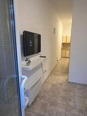 a living room with a tv on a white wall at Riva apartman in Sutomore