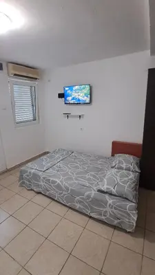 a bed in a room with a tv on the wall at B&L Apartmani in Sutomore
