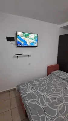 a bedroom with a bed and a flat screen tv on a wall at B&L Apartmani in Sutomore