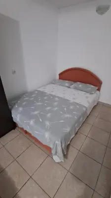 a bed with a white sheet on it in a room at B&L Apartmani in Sutomore