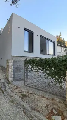 a white house with windows and a fence at B&L Apartmani in Sutomore