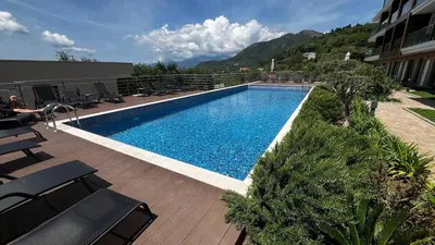 a large swimming pool with chairs and a building at Casa Montenegro Lux Apartment 1 Bedroom 1 livingroom Sea & Pool View in Tivat