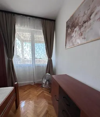 a bedroom with a dresser and a large window at Cozy one-bedroom apartment in the city center in Bar