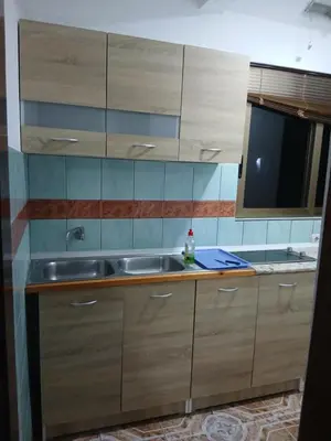 a kitchen with wooden cabinets and a sink at Apartmani OAZA 2 in Ulcinj