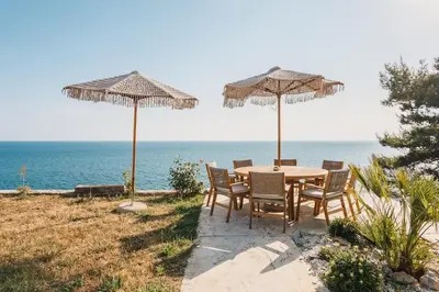 a table and chairs under umbrellas on the beach at Cottage REE in Ulcinj