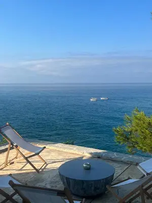 a table and a chair sitting next to the ocean at Cottage REE in Ulcinj